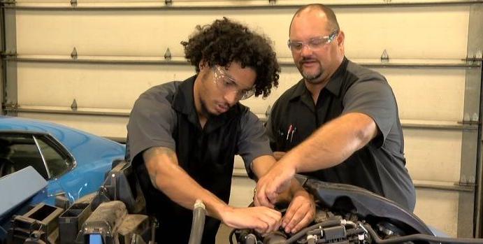 instructor helping student repair car engine